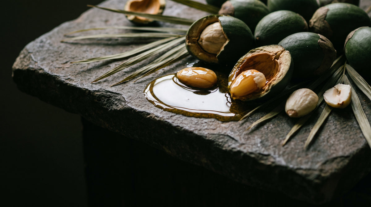 Nueces de cacay y batana con aceite dorado sobre piedra